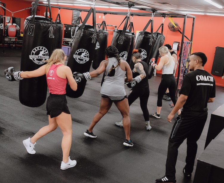 many students punching heavy bags in a cardio fitness boxing class