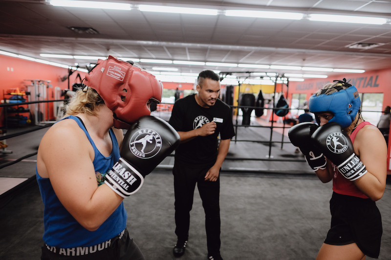 two students and coach practicing contact boxing